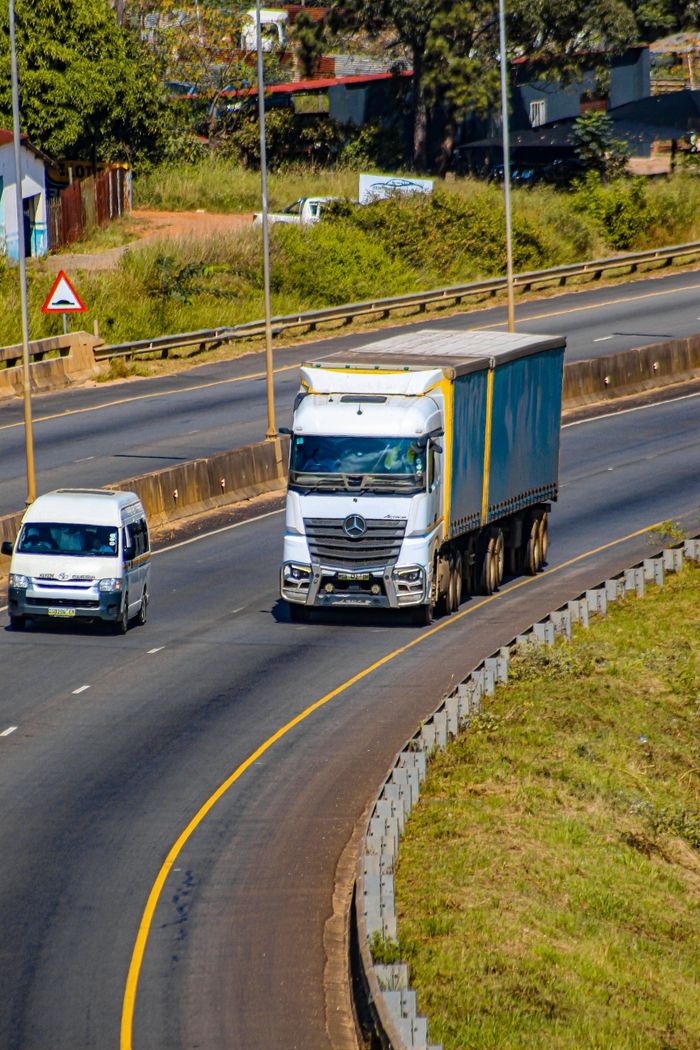 about-02 Aerial view of a highway in Eswatini showcasing a truck and van in motion on a sunny day.